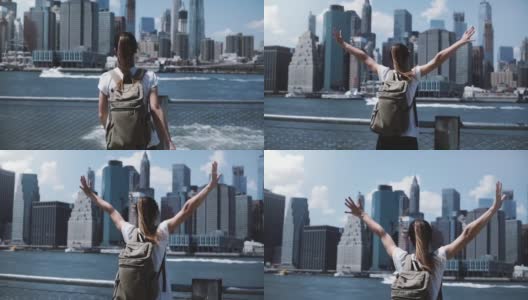 快乐的女游客背双肩包举起双臂，在纽约的天际线，看回相机高清在线视频素材下载