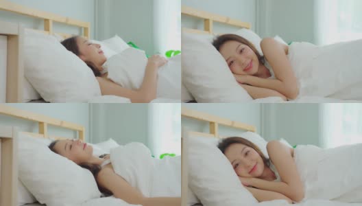 美丽迷人的亚洲女人穿着睡衣闭上眼睛微笑睡觉和甜蜜的梦在卧室的床上在早上感觉如此放松和舒适，保健和睡眠的概念高清在线视频素材下载