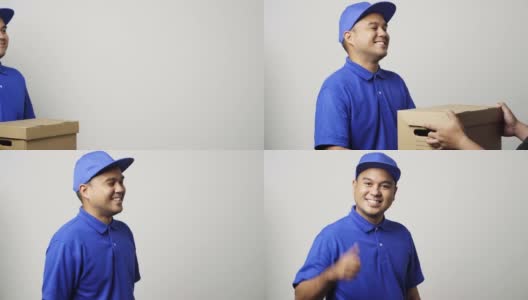 微笑的年轻亚洲快递员在蓝色制服给客户的包裹硬纸板和显示大拇指在孤立的白色背景。4 k决议。高清在线视频素材下载