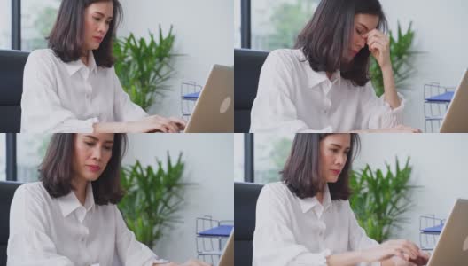 亚洲年轻女商人在电脑上工作，感到头痛的办公室。这个女人因为工作量太大而感到疲惫。办公室病综合症概念。高清在线视频素材下载