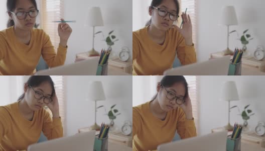 亚洲女孩正紧张地坐在家里，在笔记本电脑上与导师在线学习。提出在家在线学习的概念高清在线视频素材下载