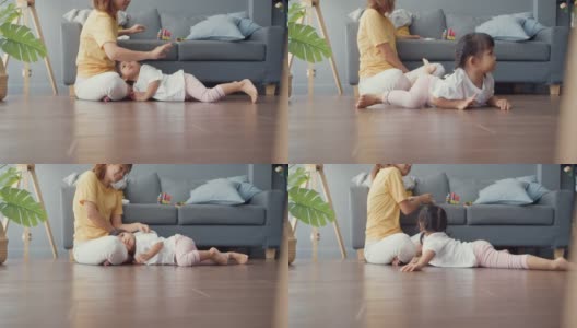 快乐快乐的亚洲家庭妈妈追逐着她可爱的烦躁的孩子，她在地板上爬行，在家里的客厅里玩耍放松。高清在线视频素材下载
