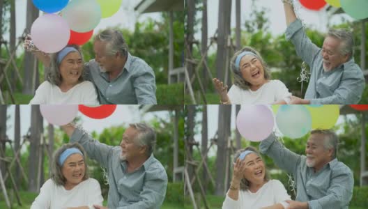 快乐的亚洲老夫妇拿着气球在家门口的草坪上。老男人和老女人在后院共度时光。一对成熟的夫妻在花园里庆祝结婚纪念日。高清在线视频素材下载