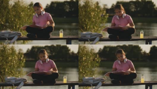小女孩在湖边看书。一个年轻的少女正在翻看一本书高清在线视频素材下载