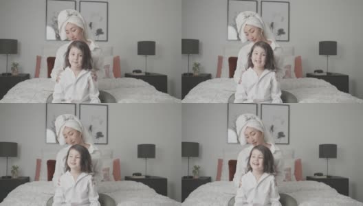 亚洲母亲假装玩身体按摩和她的女儿在床上，家庭生活方式健康的概念高清在线视频素材下载