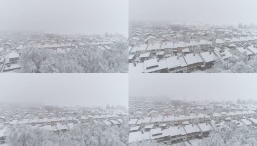 鸟瞰图:冬日里，在宁静的郊区城市里，飞翔在白雪覆盖的房屋上方高清在线视频素材下载