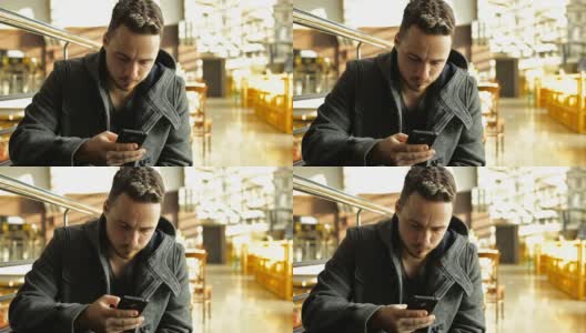 一名男子在一家大型购物中心的咖啡馆里使用电话高清在线视频素材下载