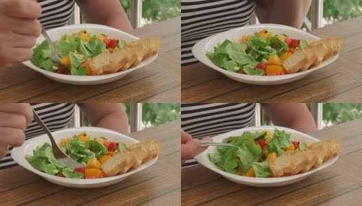 女人在外面吃清淡的午餐，在阳台上吃新鲜的蔬菜沙拉高清在线视频素材下载