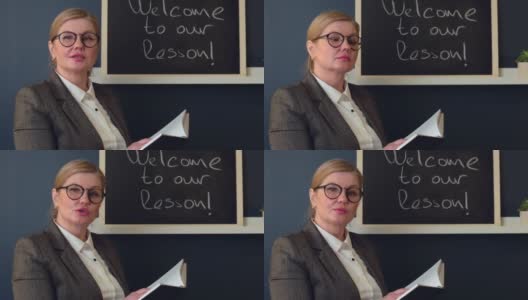 一名白种教师拿着一本书，戴着眼镜，在全班面前迎接她的第一堂课高清在线视频素材下载
