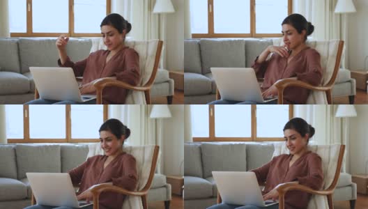 正年轻的印度女子坐在扶手椅上使用笔记本电脑高清在线视频素材下载