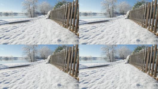 白雪覆盖的地面上有一道木栅栏，还有一只鸭子在湖里游泳高清在线视频素材下载