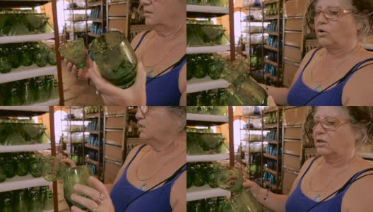 一个60岁出头的女人在购物时比较两副绿眼镜高清在线视频素材下载