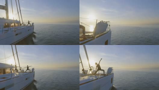 航拍侧视图拍摄的三个美丽的健康妇女做早晨瑜伽在一艘白色帆船双体船。平静的大海与升起的太阳和平静的大海。高清在线视频素材下载