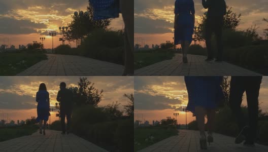 日落时分，一对年轻夫妇在秋天的公园里散步高清在线视频素材下载