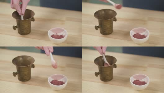 拿着勺子的女孩把铜臼里的有机粉末放进陶瓷碗里。高清在线视频素材下载