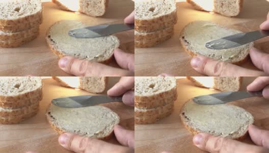 在面包上涂黄油。慢动作刀在面包表面涂黄油。特写镜头高清在线视频素材下载