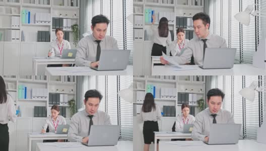 一群亚洲迷人的商业人士在办公室工作。商人和女职工坐在桌子上用笔记本电脑工作，为企业的公司项目策划。高清在线视频素材下载