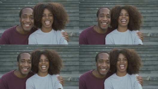 一对快乐的非洲夫妇坐在城市的楼梯上，对着镜头微笑高清在线视频素材下载