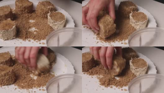 一位女士用奶油做海绵蛋糕。用饼干屑蘸蛋糕。特写镜头高清在线视频素材下载
