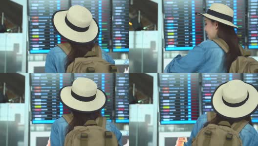 穿着旅游服装的美丽亚洲女人浏览航班时刻表的信息板。出国旅行可以用于代表独自旅行的概念作品中。高清在线视频素材下载
