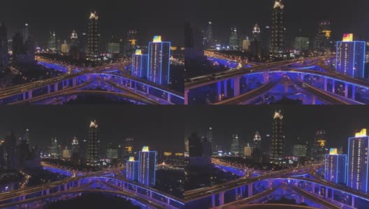 蓝色照明的夜间高架路立交桥和上海城市景观。中国鸟瞰图。无人机向后和向上飞行。远景高清在线视频素材下载
