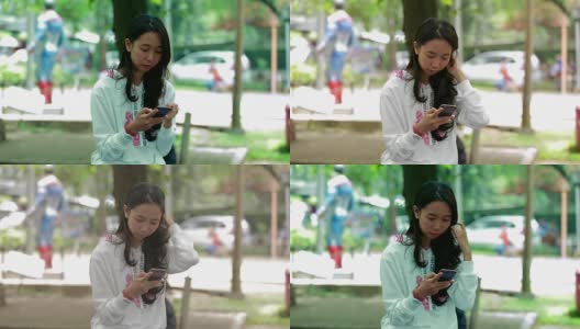 美丽的年轻东南亚女子使用手机在城市公园与三种声调高清在线视频素材下载