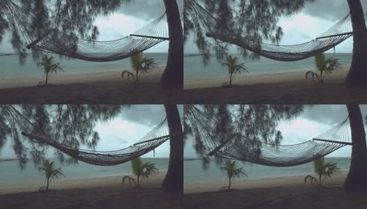 慢镜头:热带海滩上孤独的吊床在狂风暴雨中摇摆。高清在线视频素材下载