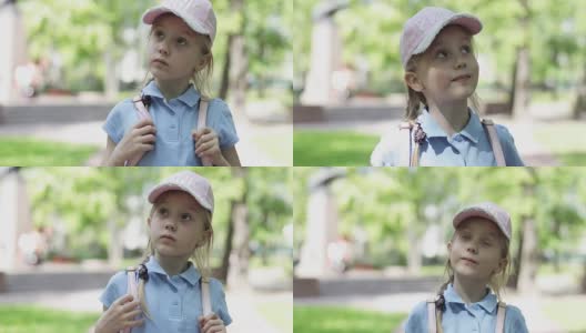 一个可爱的金发小女孩戴着帽子，穿着短裤在公园里散步。高清在线视频素材下载
