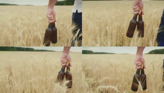 一个男人带着两瓶冰镇啤酒走过一片大麦田。这个概念是为你解渴高清在线视频素材下载