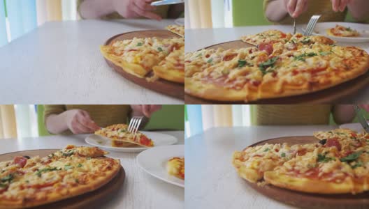 在一家餐厅的白色木制桌子上，女孩在白色盘子上切披萨。多莉拍摄高清在线视频素材下载