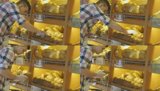 男人在超市里选了一条新鲜的面包。一个年轻人从架子上拿起一块面包闻了闻。在杂货店购物高清在线视频素材下载