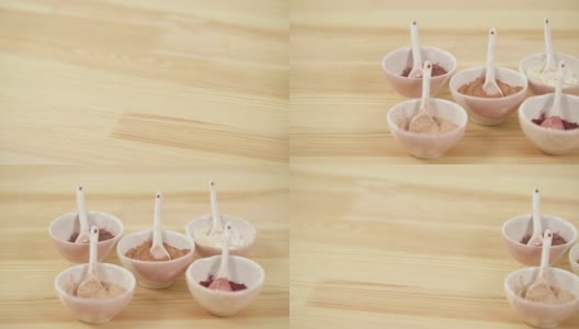 顶视图的陶瓷碗与勺子与不同的粉末在木桌上。高清在线视频素材下载