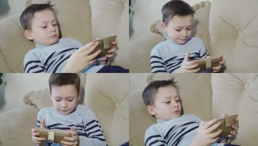 小男孩想舒服地坐在沙发上玩手机。高清在线视频素材下载