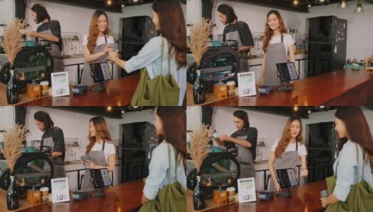 年轻的亚洲女咖啡师向亚洲顾客解释零浪费折扣促销，在咖啡馆的柜台吧台买咖啡时自己带咖啡杯，慢镜头高清在线视频素材下载