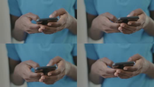 近距离拍摄的非洲裔美国青少年穿着蓝色t恤在智能手机上发短信。高清在线视频素材下载