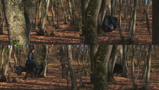在秋天的森林里奔跑的黑衣女人高清在线视频素材下载