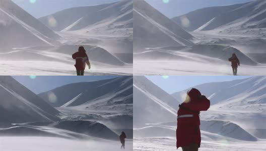 一个孤独的旅行者正穿过暴风雪，背景是雪山。高清在线视频素材下载