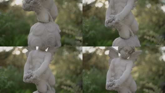 晚上在花园里的丘比特雕像。手持拍摄的高清在线视频素材下载