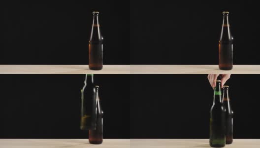 新鲜的啤酒。Hand把一个绿色的瓶子和一瓶美味的精酿啤酒放在一张黑色背景的木桌上。冰镇新鲜啤酒与水滴。准备饮料。4 k高清在线视频素材下载