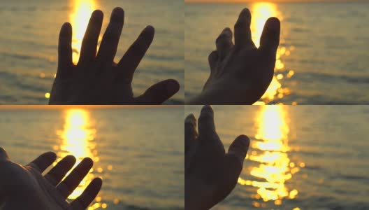 夕阳西下的海边，海边的沙滩。一个男人的手在阳光下的背景海水的性质。眩目的夕阳透过手指，旅游旅游旅行者快乐的假期夏季邮轮梦想高清在线视频素材下载