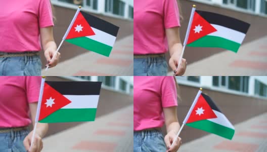 拿着约旦国旗的陌生女子。女孩举着约旦国旗走在大街上高清在线视频素材下载