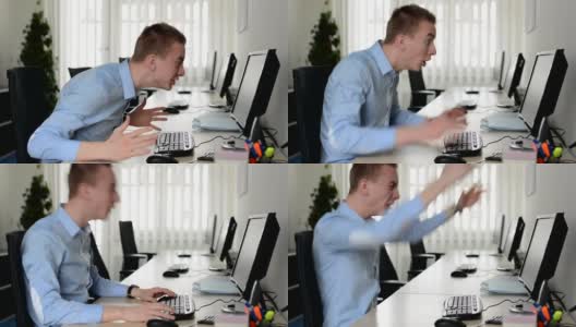 年轻英俊的男子在桌上电脑上工作，在办公室里高兴地大喊高清在线视频素材下载