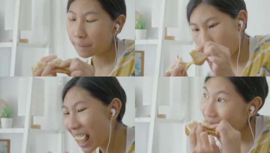 亚洲女孩一边吃着火腿烤面包一边用智能手机看电影，生活理念。高清在线视频素材下载