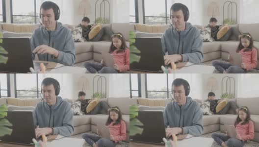 父亲在家工作陪孩子玩耍，在线缩放虚拟会议，呆在家里，成熟学生，自由职业，新常态概念高清在线视频素材下载