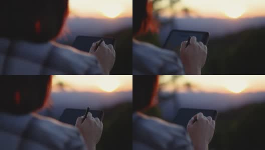 一名女子在夕阳西下的大自然中使用她的平板电脑放松时间高清在线视频素材下载