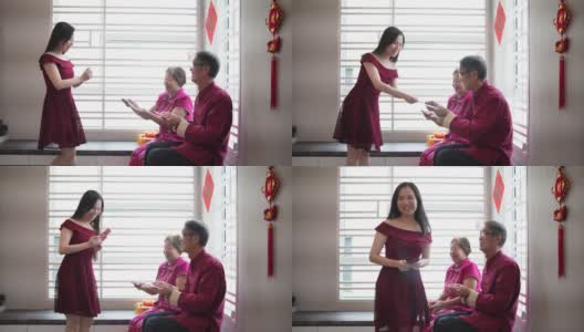 亚洲华人老人微笑着给他们的孩子红包在生活大厅中国新年高清在线视频素材下载