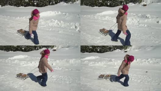 一个快乐的女孩在冬天的山上跑过一片雪林。她是笑。她身后拖着雪橇。高清在线视频素材下载