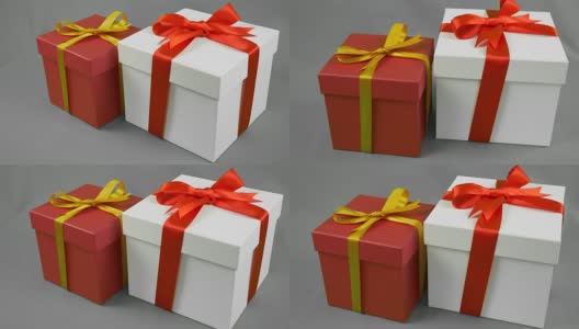 灰色背景下的两个礼品盒。白色礼盒与红色丝带蝴蝶结和红色礼盒与金黄色蝴蝶结支架。高清在线视频素材下载