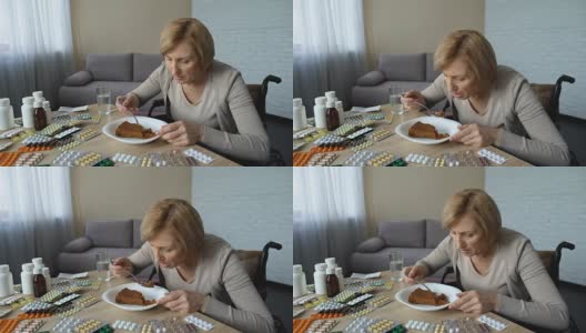 生病的残疾妇女试图在餐桌上吃甜点和药片，康复高清在线视频素材下载
