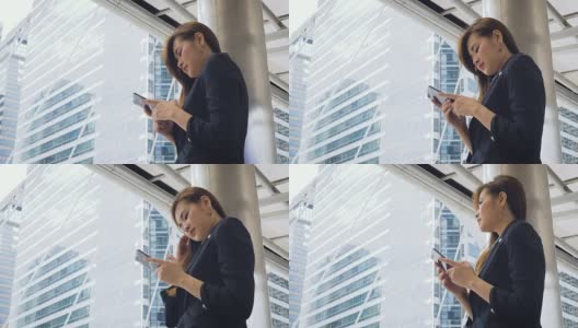 美丽的亚洲女商人手拿智能手机在外面的现代城市高清在线视频素材下载